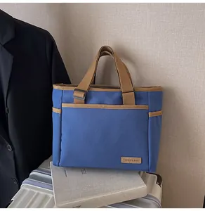 Detailaufnahme der dunkelblauen Canvas-Tasche mit khakifarbenem Lederetikett und Tasche