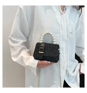 Detail of black sequin mini bag with pearl handle and golden chain shoulder strap