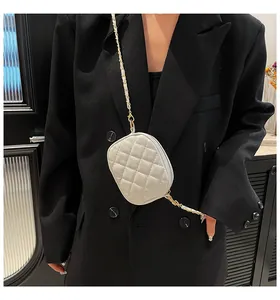 Close-up of a white quilted mini crossbody bag with gold chain strap on black blazer