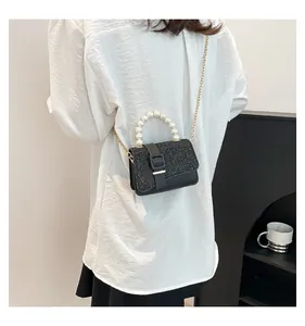 Detail of crossbody bag with pearl handle and sparkling crystal flap on black leather
