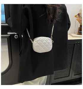 Close-up of white quilted mini crossbody bag with gold chain strap on a model