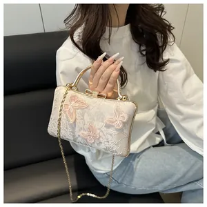 Detail of white jacquard bridal clutch featuring pink 3D butterfly appliques and gold handle