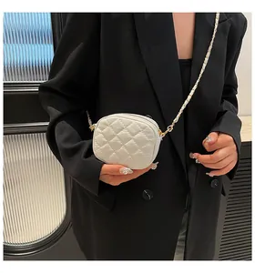 Detail of white quilted crossbody bag with gold chain strap and elegant rhombus pattern