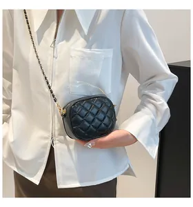 Detail of black quilted crossbody bag with golden chain strap and leather texture