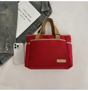 Detailaufnahme der roten Canvas-Tragetasche mit khakifarbenen Griffen und Label