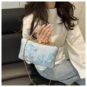 Detail of light blue evening bag with butterfly embroidery and rhinestone bow clasp