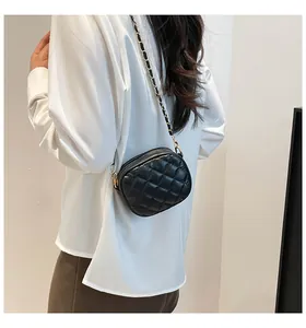 Close-up of black quilted shoulder bag with elegant gold chain strap worn by a model