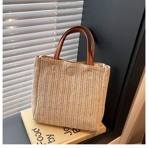 Gros plan du sac cabas en paille tissé avec poignée en cuir marron et texture