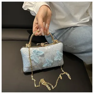 Detail of light blue lace evening bag with 3D butterfly embroidery and gold handle