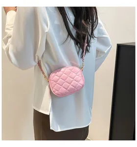 Detail of light pink quilted mini crossbody bag with chain strap on a model's back