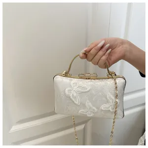 Detailed view of white jacquard fabric with embroidered butterflies and crystal bow clasp