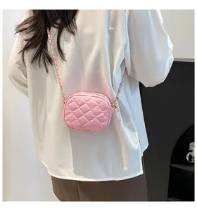 Close-up of pink quilted mini crossbody bag with gold chain strap on white shirt