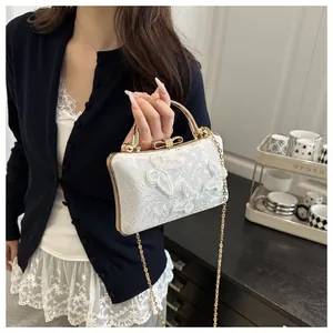 Detail of white bridal handbag featuring 3D butterfly embroidery and gold clasp