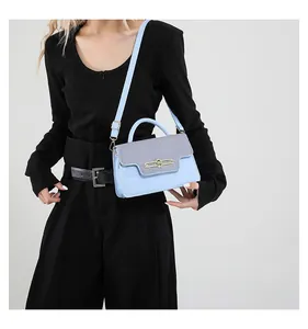 Close-up of light blue crossbody bag featuring gold buckle and woven leather texture