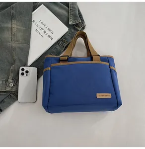 Detail der blauen Canvas-Tasche mit braunen Trägern, Fronttasche und Logo-Aufnäher
