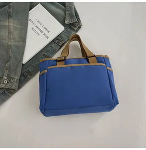 Detail der blauen Canvas-Tragetasche mit braunen Riemen, kombiniert mit einer Jeansjacke