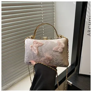 Detail of the elegant white jacquard bridal bag with 3D butterfly embroidery and gold handle