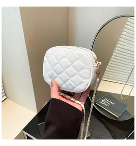 Detail shot of mini quilted white leather crossbody bag with elegant gold chain strap