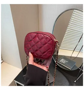 Detail of elegant dark red quilted mini crossbody bag with golden chain and sleek leather finish