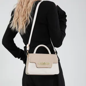 Chic beige and brown patchwork crossbody bag with gold lock shown on shoulder