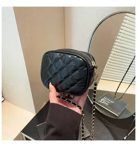 Detail of black quilted leather mini bag featuring gold zipper and chain strap