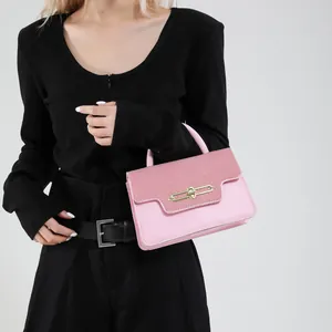 Pink minimalist crossbody bag with textured flap and gold metal buckle shown on model