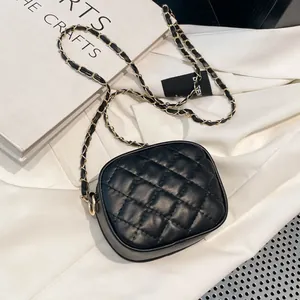 Classic black quilted leather crossbody bag with elegant gold woven chain strap on white fabric