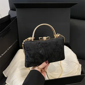 Elegant black evening clutch with floral embroidery, gold handle and bow clasp in a gift box