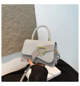 Detailed view of the gray handbag featuring a metallic D-buckle and textured sequin finish