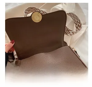 Macro detail of brown lychee leather handbag featuring magnetic snap and woven strap