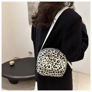 Close-up of leopard print crossbody bag featuring soft fabric and wide white shoulder strap