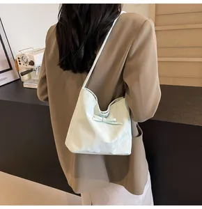 Détail d'un sac cabas vert clair avec nœud décoratif et texture plissée porté à l'épaule