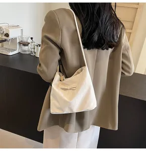 Gros plan d'un sac cabas blanc crème avec nœud décoratif dans un décor de café chaleureux