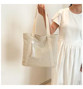 Gros plan du sac cabas tressé crème avec pendentif à franges et maille riche