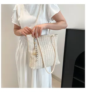Detail of beige woven straw tote bag with textured stripes and decorative ribbon charm