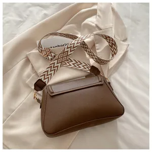 Detail of a dark brown lychee pattern leather bag with a geometric woven shoulder strap
