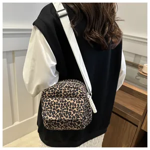 Detail view of the leopard print crossbody bag with adjustable white fabric strap