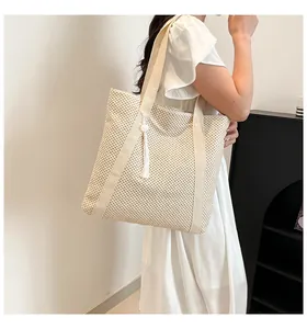 Détail d'un sac cabas tissé avec gland à franges et texture tricotée en nid d'abeille