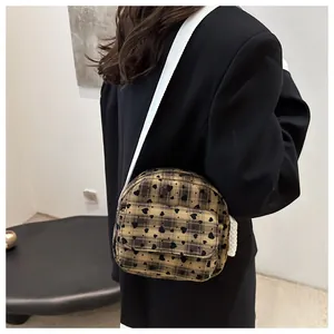 Detail of checkered crossbody bag with black heart prints and wide white fabric shoulder strap