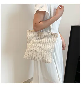 Detail of hand-woven straw tote bag with vertical stripes and thin shoulder straps