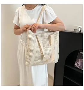 Détail du sac cabas en paille tissée blanche avec pompon et bandoulières