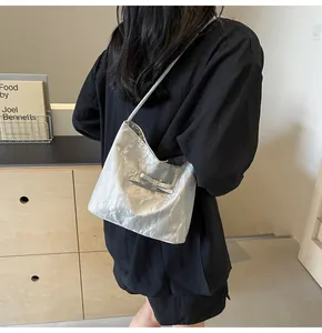 Vue détaillée d'un sac plissé argenté avec nœud porté à l'épaule par un mannequin