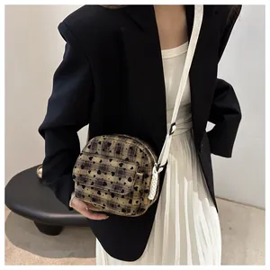 Brown checkered crossbody bag with black heart patterns worn on a black blazer
