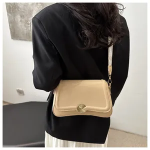 Detail of beige textured leather crossbody bag with patterned strap on female model