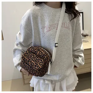 Detail of leopard print crossbody bag with adjustable white strap and front zipper pocket