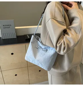 Détail du sac cabas plissé bleu clair avec un nœud décoratif sur la bandoulière