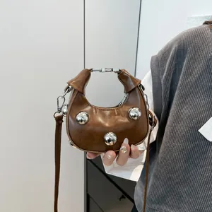 Brown semi-circular mini hobo bag with silver ball studs for handheld and crossbody wear