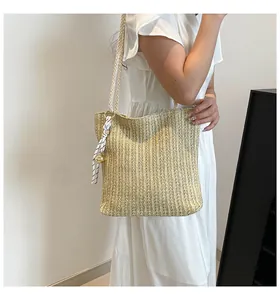 Detail of straw woven tote bag featuring a striped silk scarf and golden sphere ornament