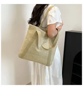 Vue latérale d'un grand sac cabas en paille avec de larges bandoulières en toile