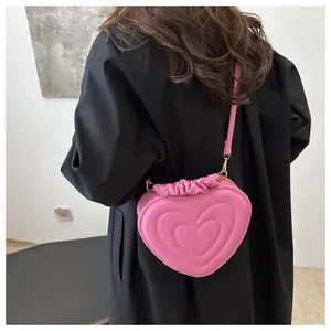 Close-up of pink heart-shaped crossbody bag with embossed patterns and ruffled edges